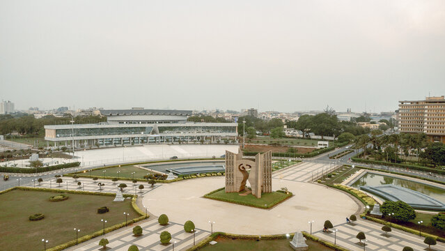 Aerial view of the Monument de l'Ind&Atilde;&copy;pendance standing proudly amidst manicured lawns and reflective pools, contrasting against the city's skyline, Lom&Atilde;&copy;, Maritime Region, Togo.