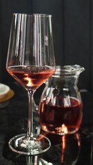 Elegant glass filled with rose wine beside a pitcher at a cozy dining table, capturing the essence of a cozy evening gathering