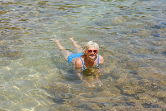 Woman is posing  in water of Mogren beach, Budva, Montenegro.