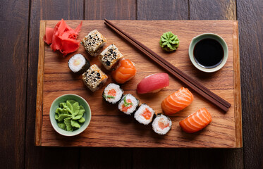Top view of a gourmet sushi platter served on a wooden board with chopsticks, soy sauce, and wasabi on the side, elegant Japanese restaurant setting, natural lighting
