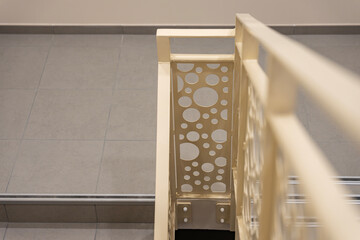 Vue sur un escalier intérieur de couleur crème, accompagné d’un garde-corps aux motifs ronds,...