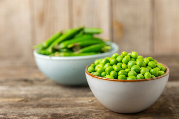 Fresh green pea pods with green peas on a wooden background. Sweet green peas. Green pea beans vegetables. Vegan. healthy vegetable. Copy space