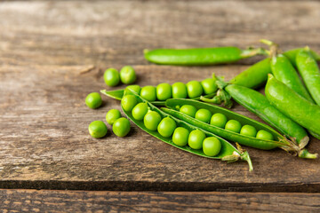 Fresh green pea pods with green peas on a wooden background. Sweet green peas. Green pea beans vegetables. Vegan. healthy vegetable. Copy space