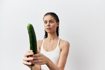 woman with a cucumber in her hand imitation sex toy on white background