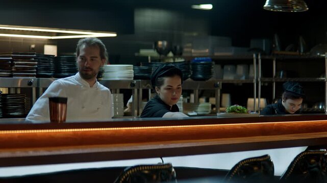 WIDE Caucasian male chef working on modern busy commercial restaurant kitchen. Shot with 2x anamorphic lens