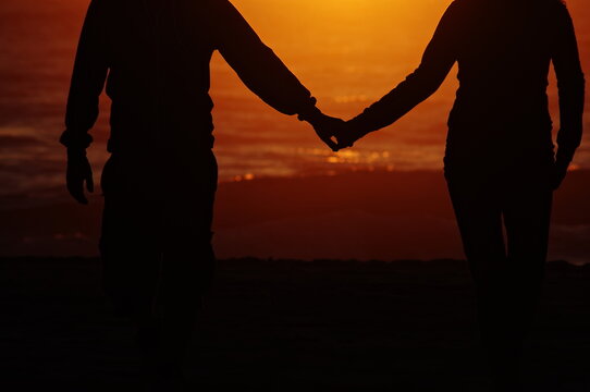 Couple holding hands on a beach at sunset