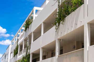 Vue en contre-plongée sur les balcons d’une résidence moderne, avec des arbustes décoratifs visibles sur plusieurs niveaux.