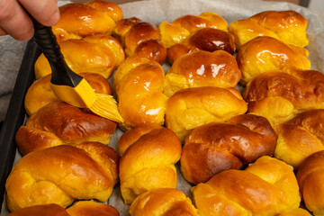 Kitchen brush smearing honey syrup on sfintisori .Romanian cuisine. Homemade Mucenici, traditional desserts made in the figure 8, smeared with honey and chopped nuts