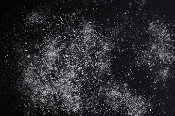 White acrylic pastel shavings on black paper texture, abstract patterned backdrop