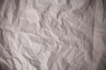 Gray recycled  paper sheet crumpled with shadowed wrinkles, soft focus close up, abstract texture
