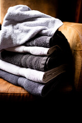 Stack of soft gray and white towels on cozy brown armchair
