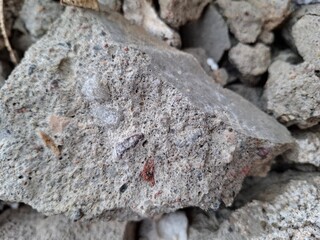 Pile of broken concrete blocks and rubble. Construction demolition waste with porous gray stone texture.
