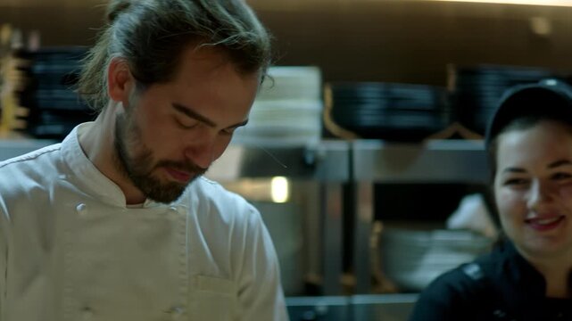 Portrait of Caucasian male chef working on busy commercial restaurant kitchen. Shot with 2x anamorphic lens