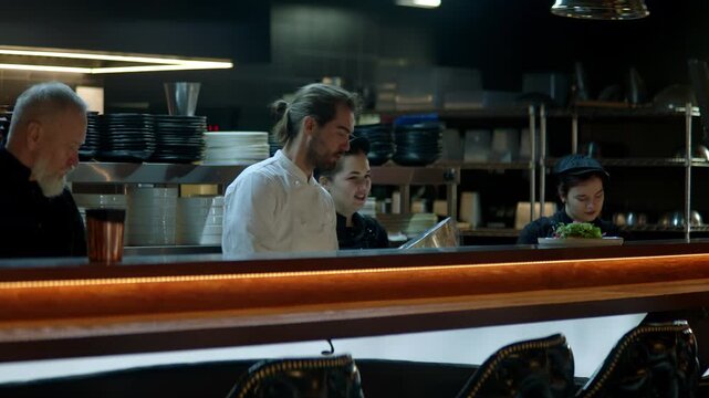 WIDE Caucasian male chef working on modern busy commercial restaurant kitchen. Shot with 2x anamorphic lens