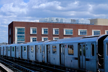 Fototapeta premium Silver Subway Cars Beside Brick School Building (Queens, New York, USA)