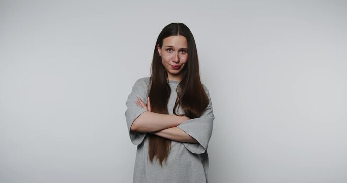 A woman stands confidently with arms crossed, sharing her thoughts in a simple, clean background. Her expression reflects sincerity and thoughtfulness.