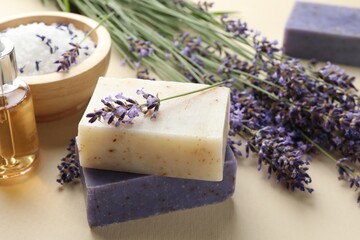 Aromatic soap bars and lavender flowers on beige background, closeup