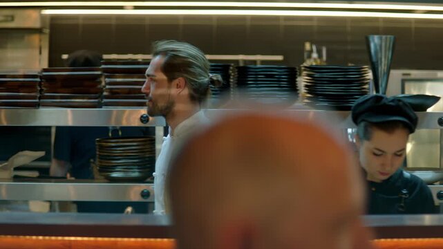 TRACKING Chef working on commercial restaurant kitchen, checking new orders on a display. Shot with 2x anamorphic lens