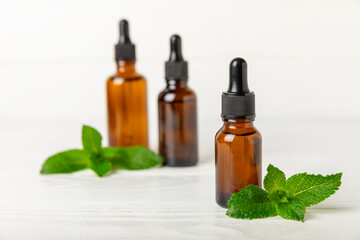 Essential oil mint on a wooden background. Peppermint essential oil with fresh mint leaves. A bottle of aromatherapy oil. Mint extract. The concept of natural cosmetics, spa care. copy space