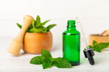Essential oil mint on a wooden background. Peppermint essential oil with fresh mint leaves. A bottle of aromatherapy oil. Mint extract. The concept of natural cosmetics, spa care. copy space