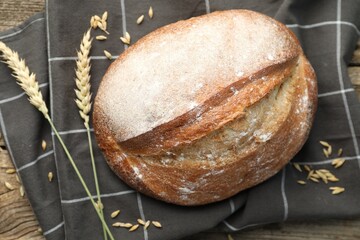 Loaf of fresh bread and spikes on table, flat lay