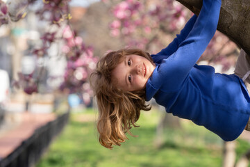 Adorable kid in spring garden. Happy childhood. Kids face near spring park. Kid Happiness. Childrens day. Cute little child under a blossom tree. Kid spring. Kids portrait in blooming cherry tree. © Volodymyr