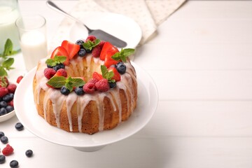 Delicious bundt cake with berries, glaze and mint on white wooden table, closeup. Space for text