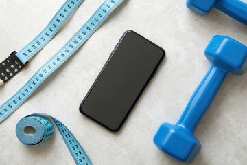 Fitness tracker, Fitness equipment including a smartphone, dumbbell, and measuring tape on a textured surface.