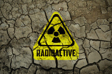 Yellow radioactive sign on cracked dry earth, top view. Radiological pollution