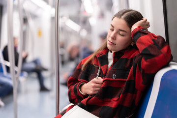 Tired European woman returns from work on the subway. Girl sitting in the subway and going to her...