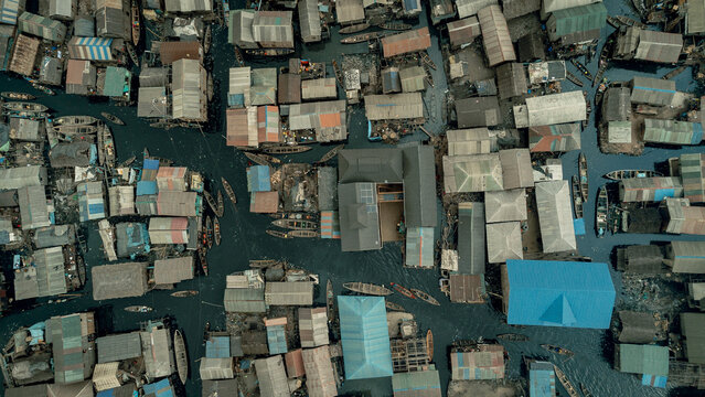 Aerial view of tightly packed buildings with colourful rooftops intermingle with waterways, creating a vibrant mosaic from above, Lagos, Lagos, Nigeria.