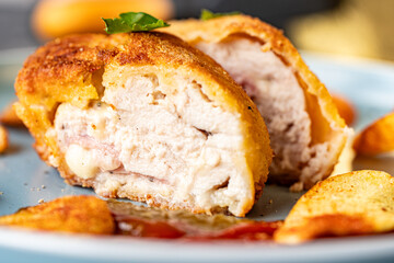 Chicken stuffed with bacon and cheese, fried in lision. A traditional French dish cordon bleu on a blue plate. Close-up