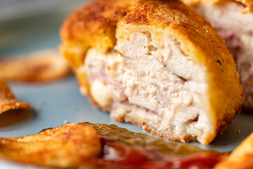 Chicken stuffed with bacon and cheese, fried in lision. A traditional French dish cordon bleu on a blue plate. Close-up