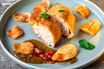 Chicken stuffed with bacon and cheese, fried in lision. A traditional French dish cordon bleu on a blue plate. Close-up