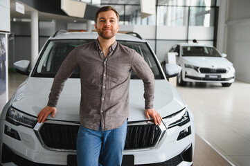 Customer leaning on new car in dealership showroom