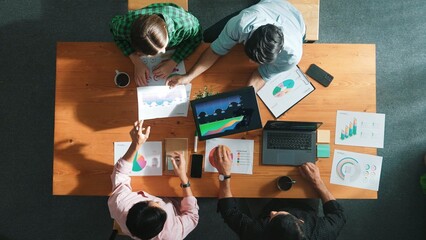 Top down aerial view of business man pointing and presenting at financial chart while diverse team...