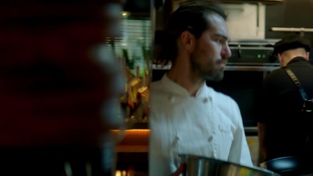 TRACKING Chef working on commercial restaurant kitchen, checking new orders on a display. Shot with 2x anamorphic lens