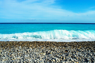 Clear turquoise sea with gentle waves under blue sky on a summer day in Nice