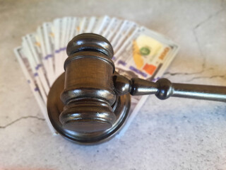 Judge's gavel and money on a cracked surface.