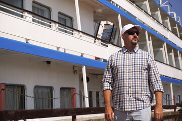 portrait of a tourist on the background of a cruise ship. A bearded man wearing sunglasses during the holidays.