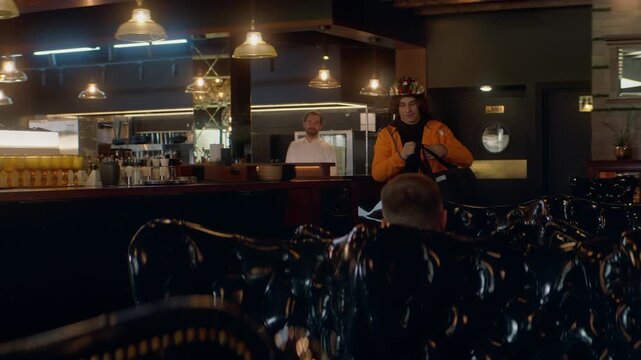 Food delivery courier in bicycle helmet entering the restaurant to pick up order for delivery. Shot with 2x anamorphic lens