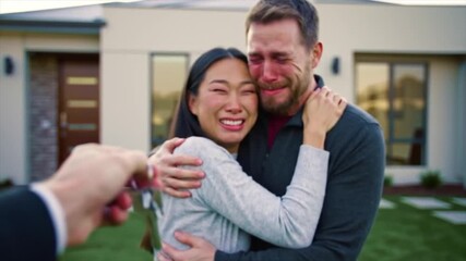 A joyful couple expresses their emotions after receiving the keys to their new home. The moment is filled with happiness, relief, and excitement as they embrace each other in celebration