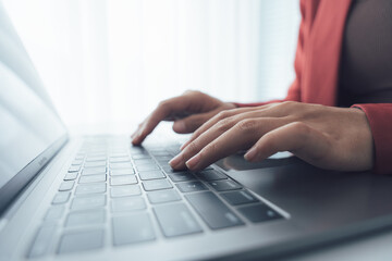 Typing on a Laptop: A close-up shot captures a person's hands typing diligently on a laptop keyboard, the image emphasizing digital communication and focused work