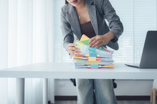 Diligent Office Worker: A focused individual meticulously organizes a stack of important documents, highlighting the commitment to professionalism and meticulous detail within a modern office setting.