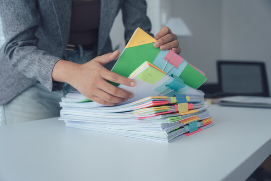 Business woman working with documents: A diligent businesswoman navigates a stack of organized documents, signifying her commitment to paperwork and administrative tasks.