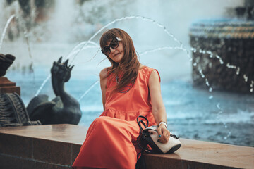 woman in glasses sits near a fountain