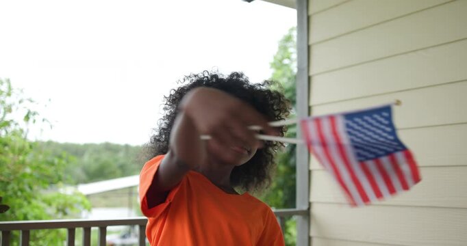Slow motion Joyful girl hold and swing American flag celebrating outdoors with waving American flags on U.S. Independence Day.enjoying a festive patriotic event