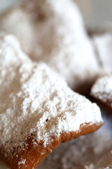 A close up of beignets covered in powered sugar 