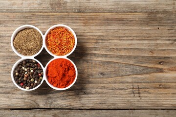 Different aromatic spices on wooden table, flat lay. Space for text