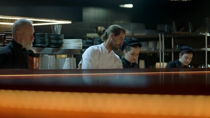 WIDE Caucasian male chef working on modern busy commercial restaurant kitchen. Shot with 2x anamorphic lens